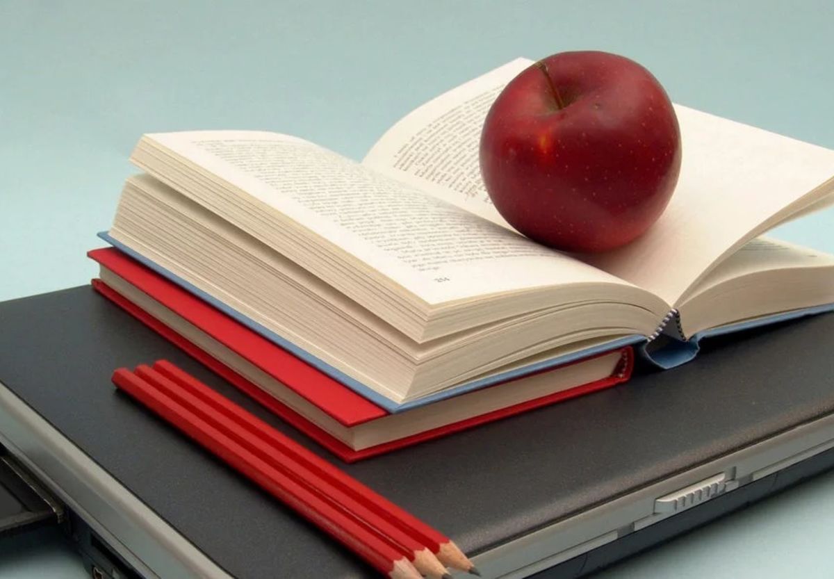 apple on top of book and a laptop- representing acedemia